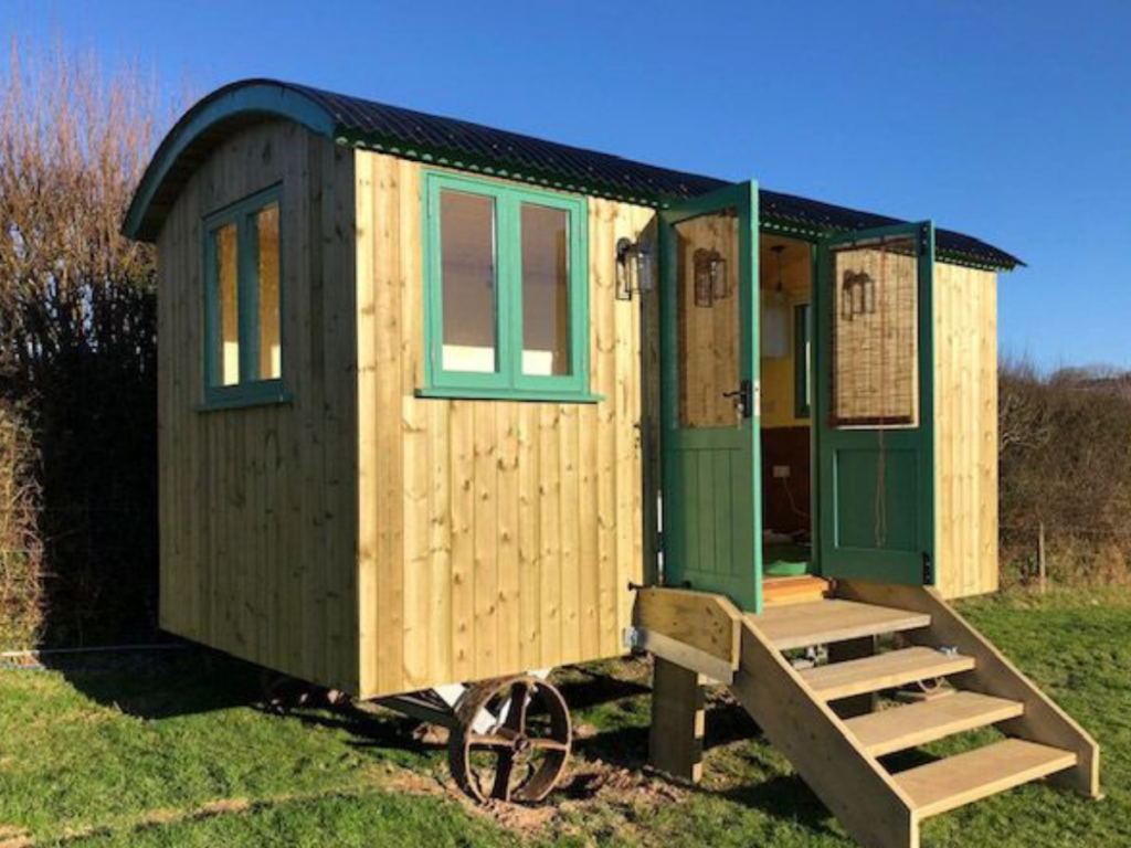 A glamping structure with green doors and a green roof.