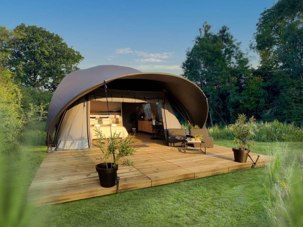 A glamping structure in the middle of a grassy field.